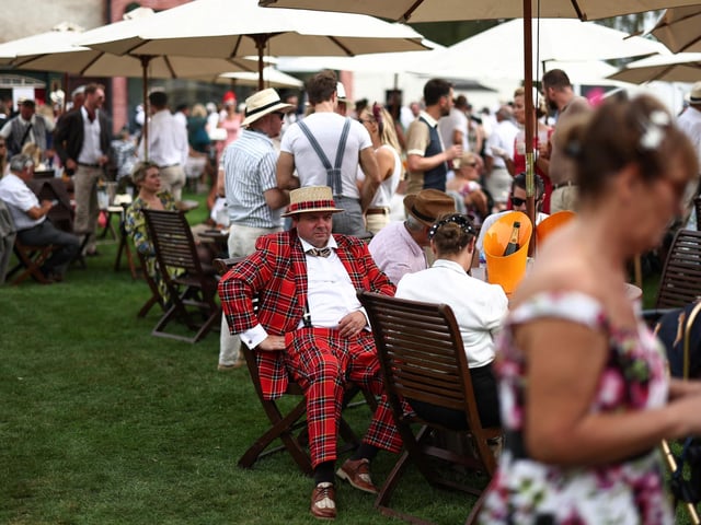 People wearing period clothing attend the opening day of Goodwood Revival at the Goodwood Motor Circuit in Chichester on September 8, 2023. The only historic motor race meeting to be staged entirely in a period theme, Goodwood Revival is an immersive celebration of iconic cars and fashion. (Photo by HENRY NICHOLLS / AFP) (Photo by HENRY NICHOLLS/AFP via Getty Images)