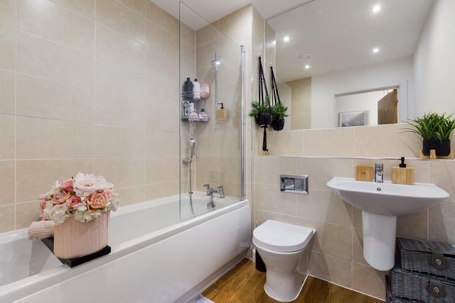 The bathroom has a contemporary white suite with a shower over bath and a large full wall mirror.
