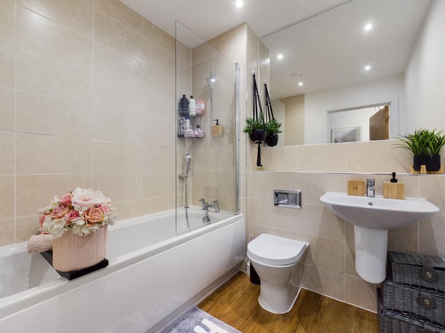 The bathroom has a contemporary white suite with a shower over bath and a large full wall mirror.