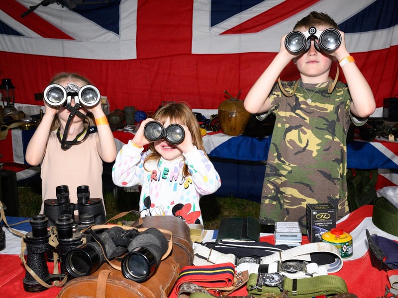 Phoenix, Isla, and Caelen try out the binoculars at a trade stand.Picture: Keith Woodland (260521-40)
