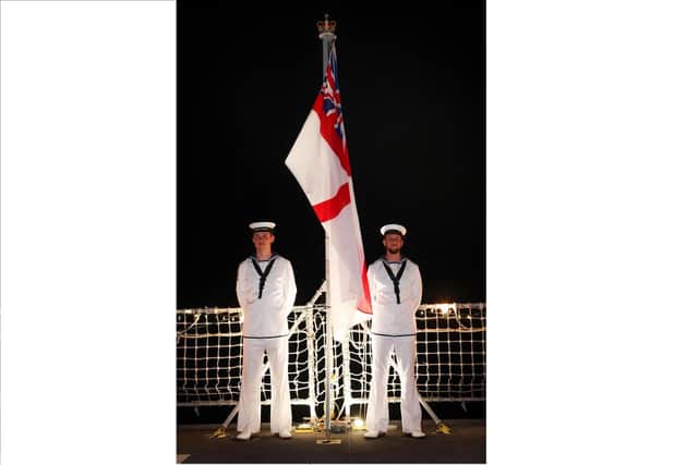 Members of HMS Tamar's Ceremonial Sunset Party standby to haul down the ship's White Ensign during a reception held on the ships flight deck Picture: LPhot Lee Blease