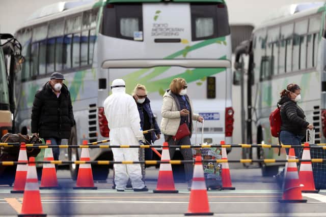 Foreign passengers from the quarantined Diamond Princess cruise ship leave a port in Yokohama, near Tokyo, Thursday, Feb. 20, 2020. Passengers tested negative for COVID-19 started disembarking since Wednesday. (AP Photo/Eugene Hoshiko)