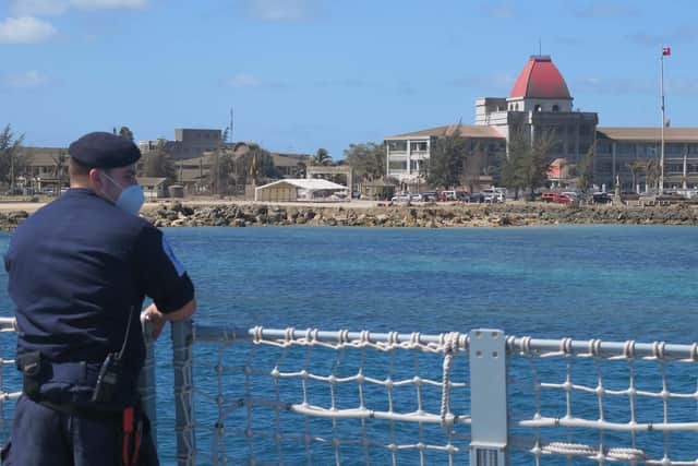 A Royal Navy sailor looks inland where residual ash and debris are noticeable on buildings and vegetation in the Tongan capital of Nuku’alofa.
