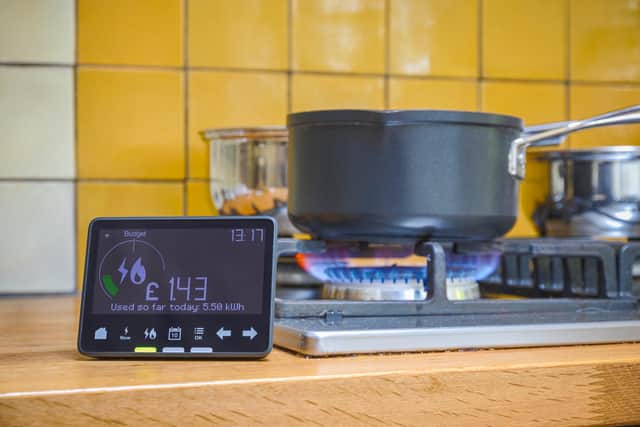 Smart meter placed next to gas stove with blue flames burning