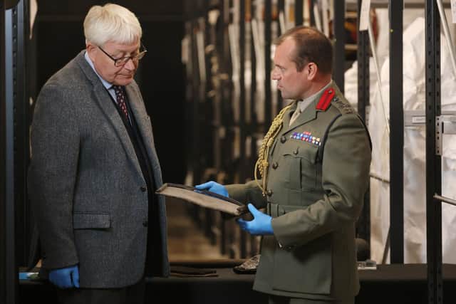 Member of staff from The National Museum of Royal Navy showing a historic artifact to Brigadier Jock Fraser MBE ADC.
