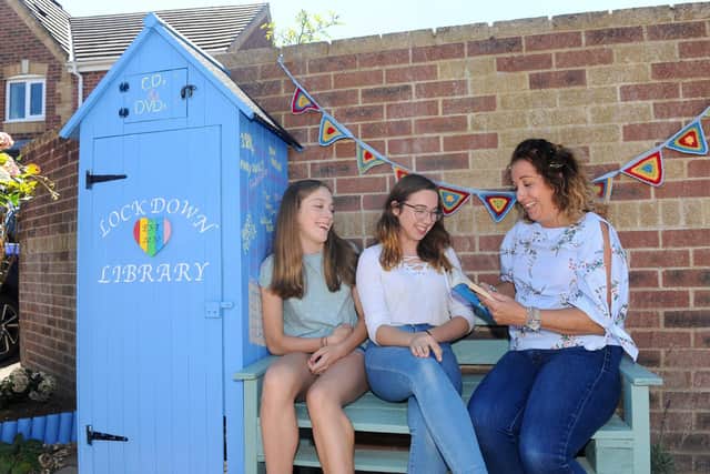 Sarah Kirby from Camelia Close in Denvilles, and her daughters set up a box at the end of their driveway during lockdown for neighbours to take books from, and through a fundraiser they have managed to create a permanent lockdown library at the end of the road with a bench and a community herb garden. Pictured is: (right) Sarah Kirby (49) with her daughters (left) Hannah (15) and Alice (18) at the Lockdown Library.Picture: Sarah Standing (060820-2133)