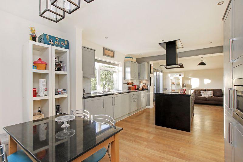 The kitchen has fitted units and contains a central island with a breakfast bar. Included within the sale is an integrated oven, hob with an extractor above, a microwave oven, dishwasher, two fridges and a freezer.