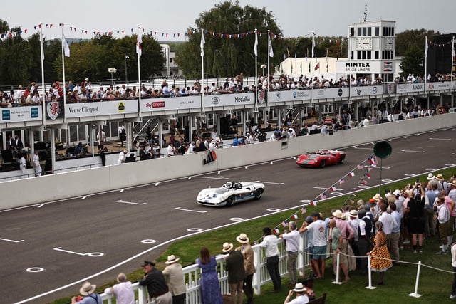 Racegoers watch as classic cars take part in a race during the opening day of Goodwood Revival at the Goodwood Motor Circuit in Chichester on September 8, 2023. The only historic motor race meeting to be staged entirely in a period theme, Goodwood Revival is an immersive celebration of iconic cars and fashion. (Photo by HENRY NICHOLLS / AFP) (Photo by HENRY NICHOLLS/AFP via Getty Images)