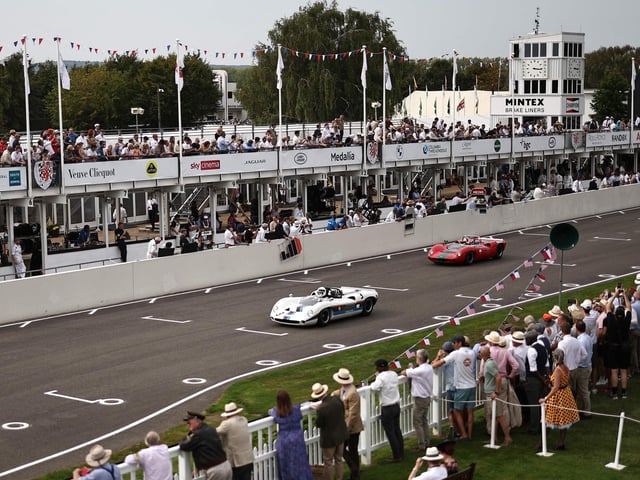Racegoers watch as classic cars take part in a race during the opening day of Goodwood Revival at the Goodwood Motor Circuit in Chichester on September 8, 2023. The only historic motor race meeting to be staged entirely in a period theme, Goodwood Revival is an immersive celebration of iconic cars and fashion. (Photo by HENRY NICHOLLS / AFP) (Photo by HENRY NICHOLLS/AFP via Getty Images)