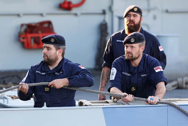 Crew from HMS Severn preparing to bring the ship along HMS Belfast on the River Thames in London