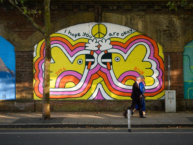 Pictured is: A couple walk past one of the many artworks along the railway arches by the Hard.Picture: Keith Woodland (140921-114)