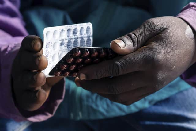 An HIV positive TB patient, holds a packet of tablets received as part of his treatment. Photo: Jekesai Njikizana/AFP via Getty Images
