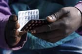 An HIV positive TB patient, holds a packet of tablets received as part of his treatment. Photo: Jekesai Njikizana/AFP via Getty Images