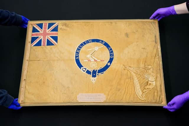 Conservators from the National Museum of the Royal Navy move the Kellet Sledge flag after it was taken out of it's frame for inspection at Portsmouth Historic Dockyard in Hampshire. Picture: Andrew Matthews/PA Wire.