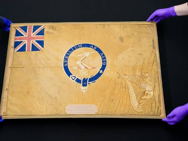 Conservators from the National Museum of the Royal Navy move the Kellet Sledge flag after it was taken out of it's frame for inspection at Portsmouth Historic Dockyard in Hampshire. Picture: Andrew Matthews/PA Wire.