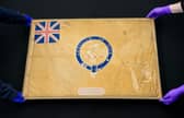 Conservators from the National Museum of the Royal Navy move the Kellet Sledge flag after it was taken out of it's frame for inspection at Portsmouth Historic Dockyard in Hampshire. Picture: Andrew Matthews/PA Wire.