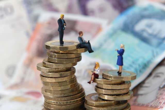 Models of men and women on a pile of coins and bank notes.