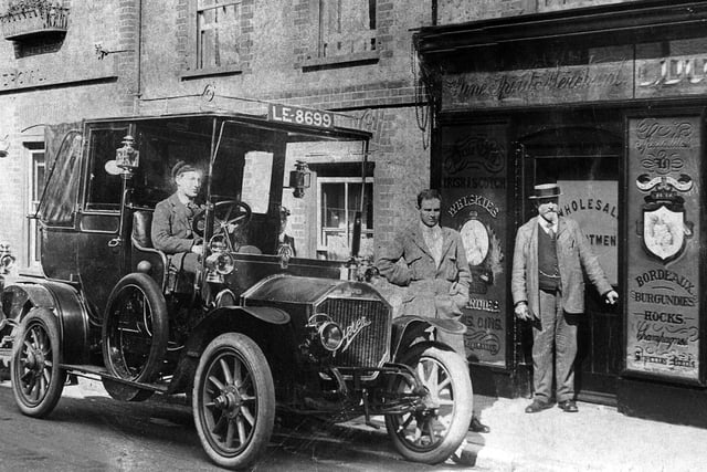 Chauffeurs waiting for guests outside the Bear Hotel, East Street, Havant. The Bear Hotel was built c.1747, according to the deeds of the property. The gentlemen next door are at a wholesale shop selling Irish and Scotch Whiskies, Champagnes, Bordaeux and Burgundies and Hocks.