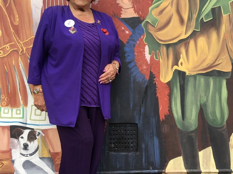 Irene Strange of Southsea wearing her red hat next to her depiction on Mark Lewis' mural in Clarendon Road