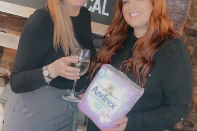 Landlady Hayley Hodd, left, 38, exchanges a glass of wine for a pack of toilet rolls with customer, Victoria Marshall.