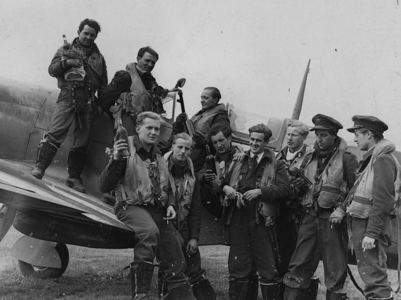 Pilots from a Spitfire Squadron, who have returned from a French attack, holding bottles of wine. Pictured: June 29 1944: (Photo by Harry Shepherd/Fox Photos/Getty Images)