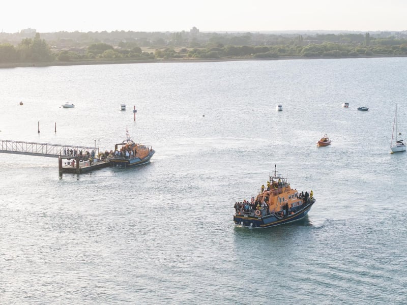 Around 140 migrants arrive in Portsmouth, Hampshire after being transferred from a single dingy south of the Isle of Wight in the English Channel by two RNLI lifeboats, a mammoth operation is talking place on Sunday evening to process the illegal migrants, with dozens of government workers from Police, Border Force, Ambulance and Fire crews, along with a number of transport busses. Viewed from Hayling Island, just across the water. Dated 06/09/26.