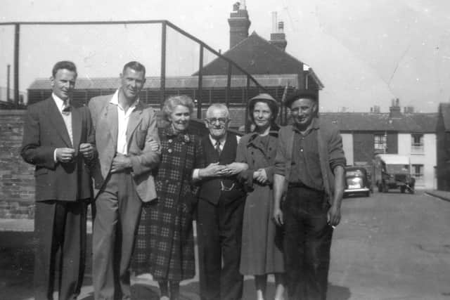 Residents outside the Delhi Tavern. A French onion Johnny on the right. Wellington Place school play gound to the rear.