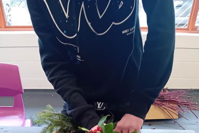 A student puts the finishing touches to a handmade Christmas wreath during a practical workshop led by Mitie’s grounds team.