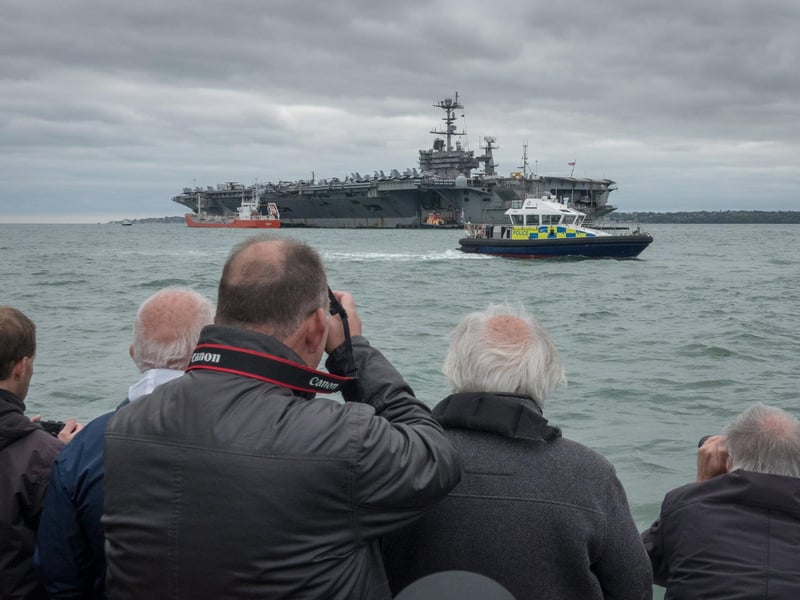 Sightseers take photographs of the US warship USS Harry S. Truman, anchored in the Solent on October 8, 2018 near Portsmouth.
