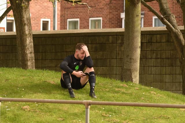 US Portsmouth keeper Tom Price sits alone on a grass bank at one end of the Victory Stadium after his side's FA Vase semi-final loss. Picture: Keith Woodland.