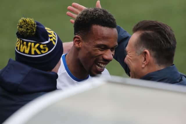 Manny Duku wears a broad smile after coming off following his goal. Also pictured are Hawks assistant boss Ian Baird, left, and manager Paul Doswell. Picture: Dave Haines.