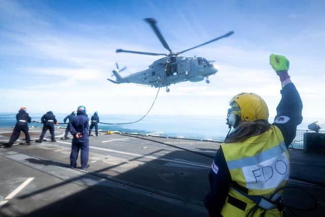 A Merlin helicopter hovers above Portsmouth-based frigate HMS Westminster as deck crew from the ship help to refuel it. Photo: Royal Navy