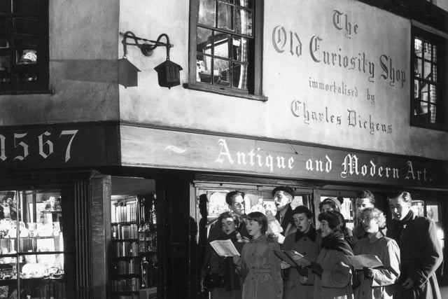12th December 1956:  Students of King's College singing Christmas carols outside the Old Curiosity Shop, as immortalised by Charles Dickens, in Portsmouth Street, London.  (Photo by Topical Press Agency/Getty Images)