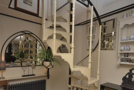 At the far end of the kitchen, a spiral staircase leads up to a bedroom and modern bathroom.