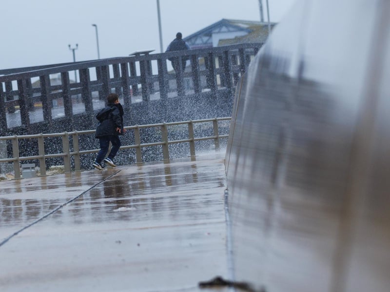 The stormy sea at high tide crashed waves onto footpaths as passer-by's did their best to get out the way