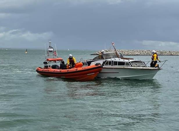 The motor-cruiser is helped into Cowes Harbour by the lifeboat.
