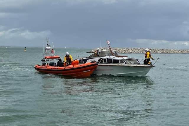 The motor-cruiser is helped into Cowes Harbour by the lifeboat.