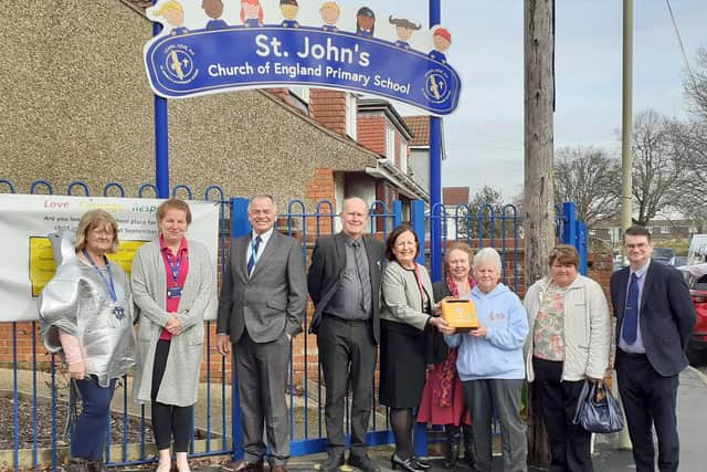 A crowd gathers at St. John's Church of England Primary School as the team accepts the defibrillator donation from Elizabeth.