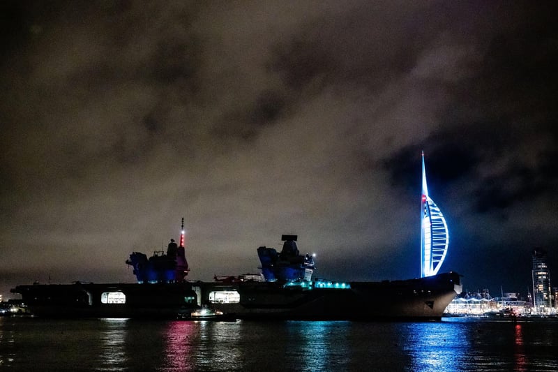 HMS Queen Elizabeth sailing past the Spinnaker Tower illuminated in colours for Elin Martin.