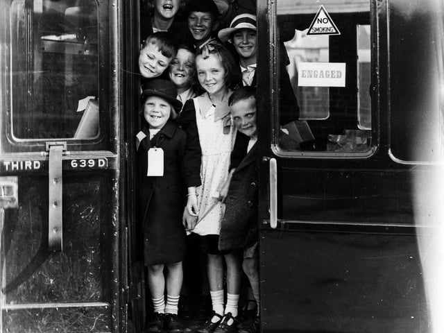 Evacuees smile for the camera as they board a train. The News PP306