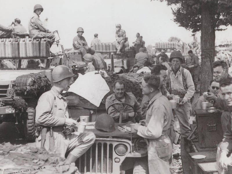 US troops having a roadside break. The number of fuel (jerry) cans carried by the vehicles on the left suggests they are going quite a distance.