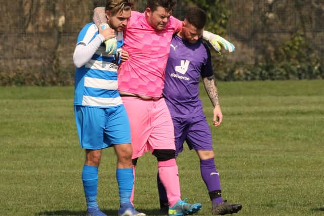 The Old Boys Athletic keeper is helped off the pitch after being injured against AC Copnor. Picture by Kevin Shipp