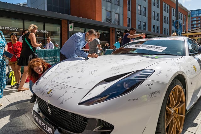 Visitors to Gunwharf participating in the Guinness World record attempt by signing the Ferrari 812 Superfast. 
Picture: Mike Cooter (290723)