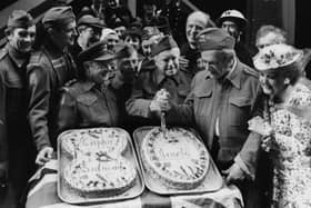 The cast of the BBC television show 'Dad's Army' in costume; (L-R) Talfryn Thomas, Ian Lavender, Arthur Lowe, Clive Dunn, Arnold Ridley and John le Mesurier, with Bill Pertwee and Frank Williams in the background, cutting a cake to celebrate the 80th birthday of Arnold Ridley on stage at the Shaftesbury Theatre, London, January 7th 1976. (Photo by Frank Barratt/Keystone/Getty Images)