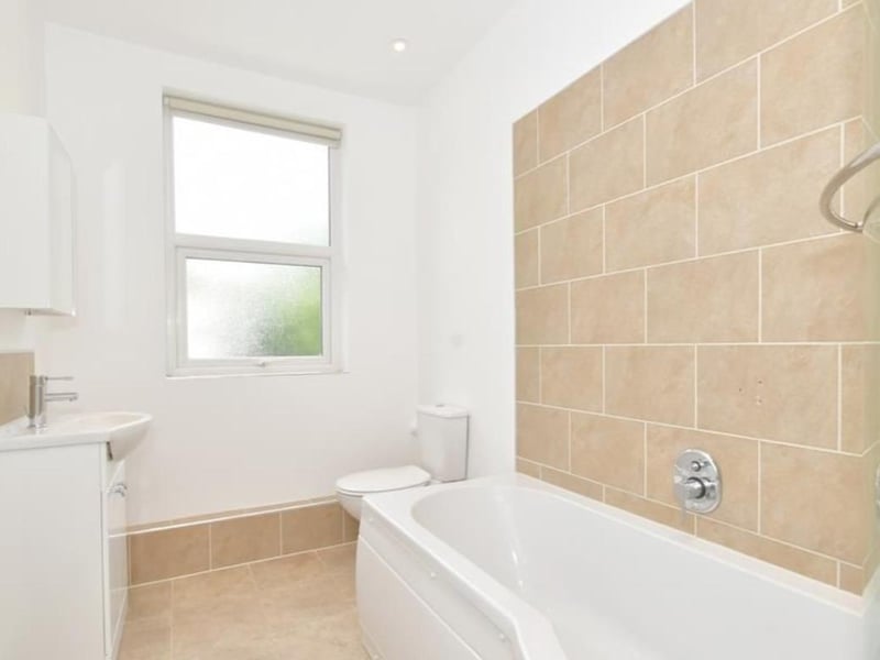 The bath has a shower over head and is contemporary.