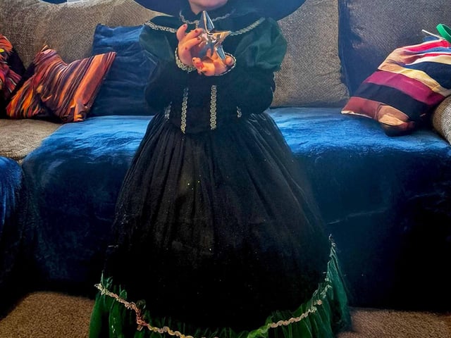 Dulcie with her Cancer Research UK for Children and Young People Star Award, wearing a 'Wicked' dress she bought with her TK Maxx vouchers