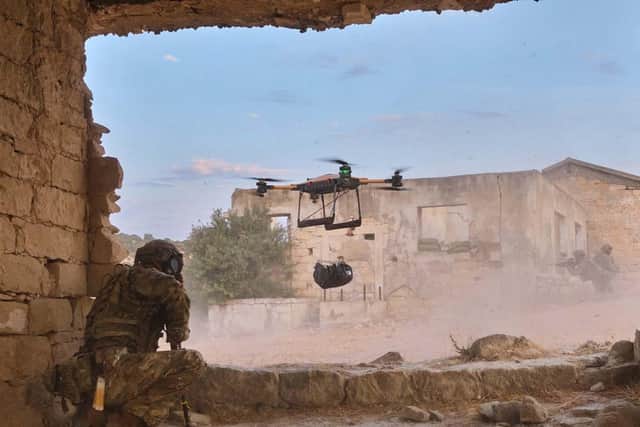 A Malloy drone drops a bag of supplies to a waiting Royal Marine.