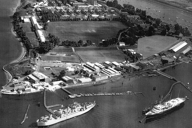 HMS Excellent on Whale Island aerial view 1970. Bottom right at her mooring is the Royal Yacht Britannia where she was always located when not in use. The grey ship to the left is HMS Rame Head that was a Canadian ship. She was a training ship later followed by HMS Bristol which still uses the birth to this day. Just above the playing field are the barrack blocks.
