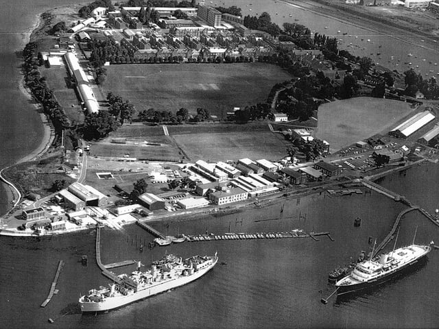 HMS Excellent on Whale Island aerial view 1970. Bottom right at her mooring is the Royal Yacht Britannia where she was always located when not in use. The grey ship to the left is HMS Rame Head that was a Canadian ship. She was a training ship later followed by HMS Bristol which still uses the birth to this day. Just above the playing field are the barrack blocks.
