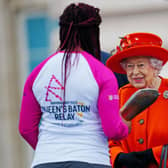 Queen Elizabeth II passes her baton to the baton bearer, British parasport athlete Kadeena Cox, during the launch of the Queen's Baton Relay for Birmingham 2022, the XXII Commonwealth Games at Buckingham Palace on October 7, 2021 in London, England. The Queen and The Earl of Wessex are Patron and Vice-Patron of the Commonwealth Games Federation respectively. (Photo by Victoria Jones - WPA Pool/Getty Images)